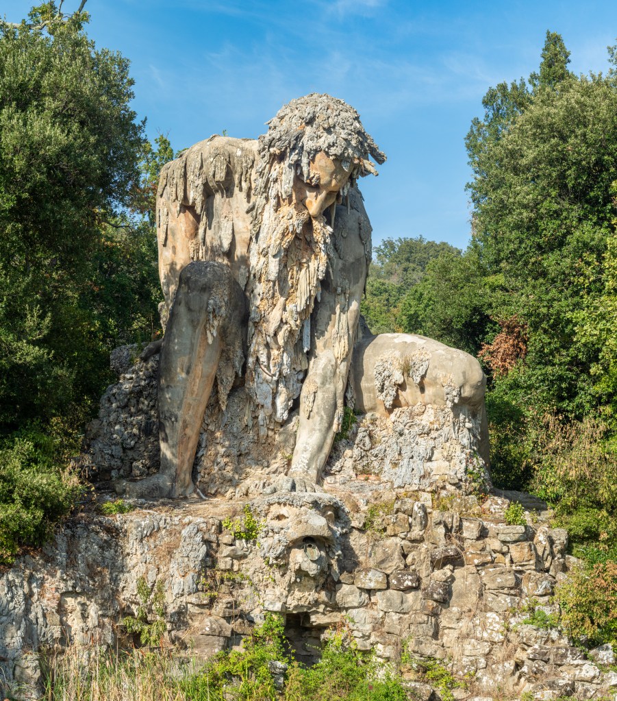 A statue of a seated giant looking into the water.