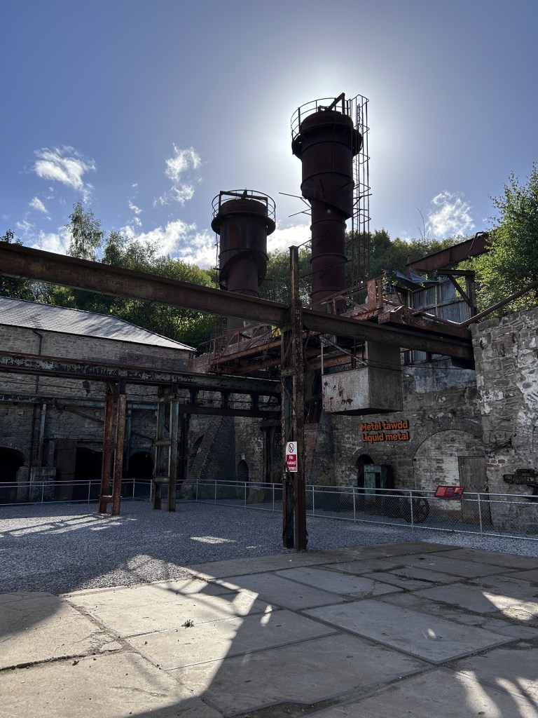 Two metal towers with the Sun behind them. High walls but no roof. The area looks like an open courtyard.
