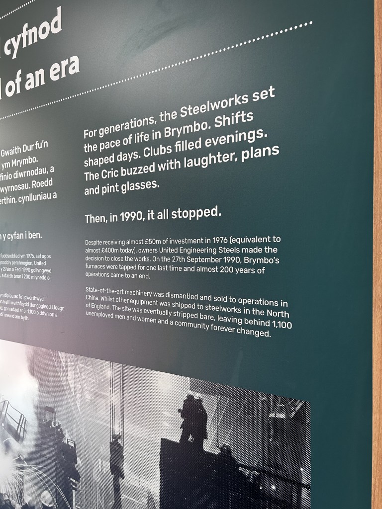 Museum display board. Text reads: "Then, in 1990, it all stopped. Despite receiving almost £50m of investment in 1976 (equivalent to almost £400m today), owners United Engineering Steels made the decision to close the works. On the 27th September 1990, Brymbo's furnaces were tapped for one last time and almost 200 years of operations came to an end."
