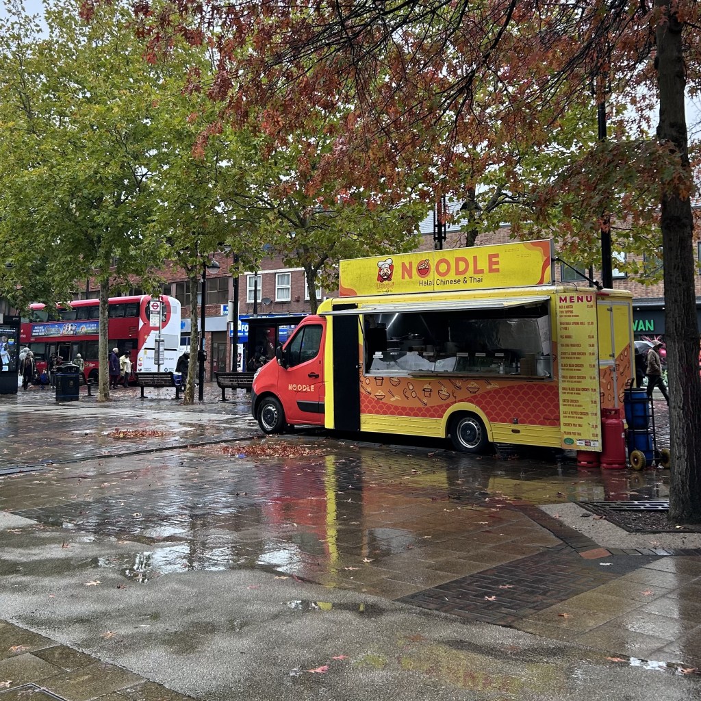 A truck selling noodles (Halal Chinese and Thai). The truck is red and yellow.